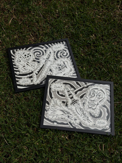 Two black-framed black and grey tattoo flash sheets by Indi Giblin, photographed together on grass.